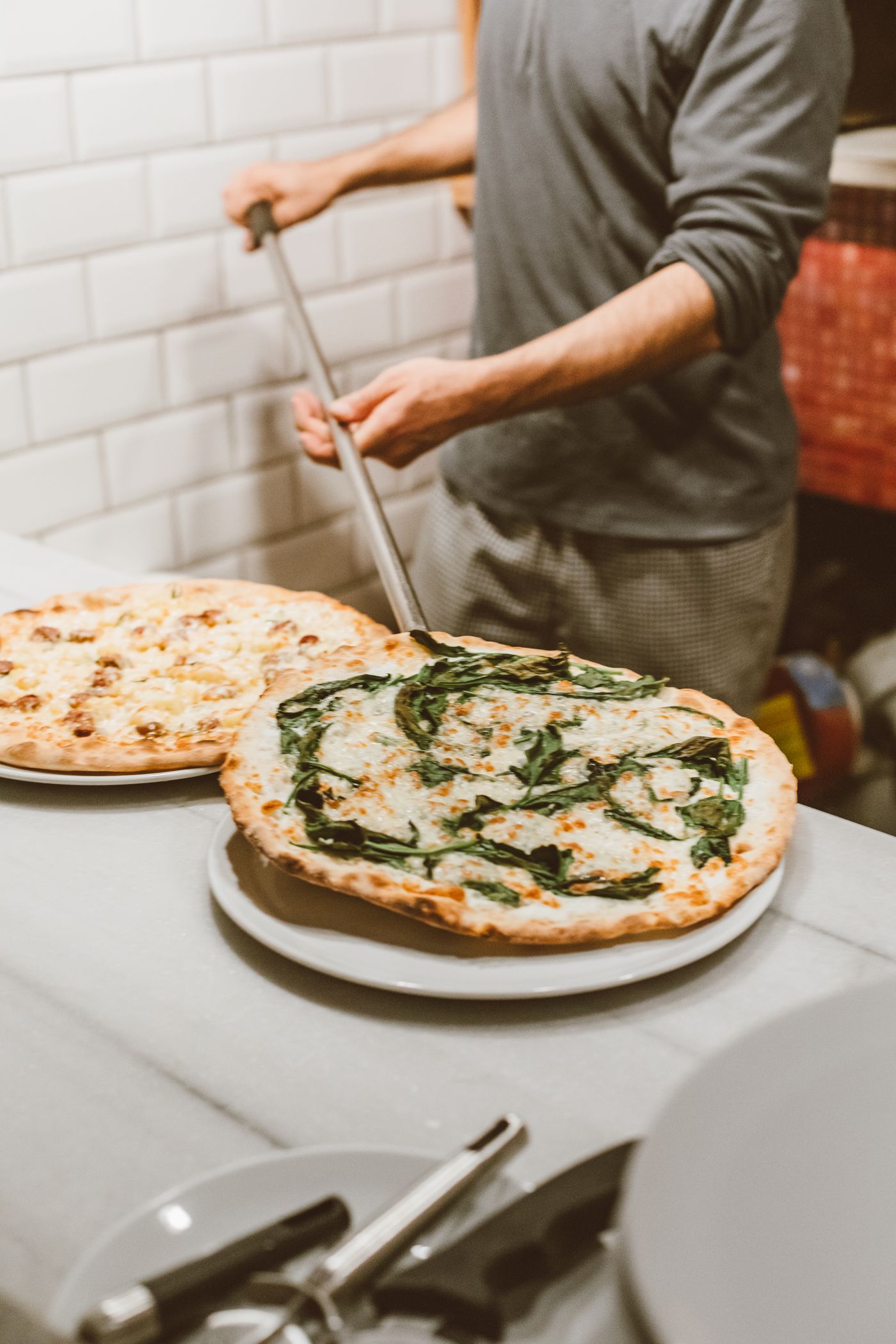 Le pizzaiolo dresse deux pizzas tout juste sorties du four